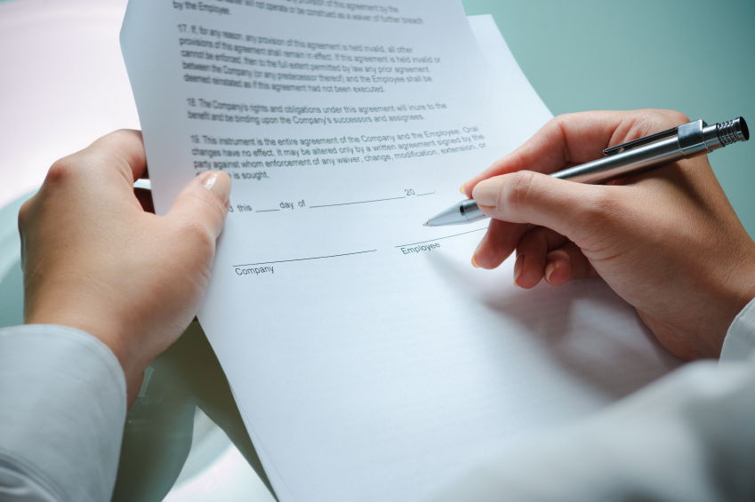 hands signing an employment agreement