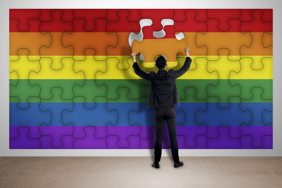 man putting together final jigsaw pieces to complete a Pride flag